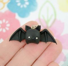 a small black bat shaped keychain sitting on someone's hand