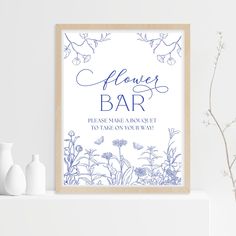 a blue and white flower bar sign sitting on top of a shelf next to vases