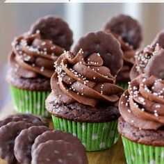 cupcakes with chocolate frosting and sprinkles are on a cutting board