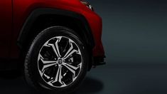 the front wheel of a red suv with white spokes and black tires on a dark background