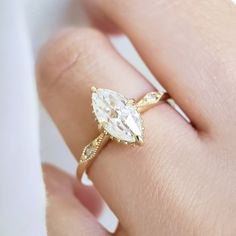 a woman's hand with a yellow gold ring and a pear shaped diamond on it