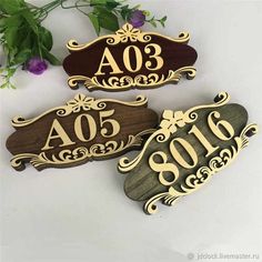 three wooden plaques with the names ao and ao written in gold on them, sitting next to some purple flowers