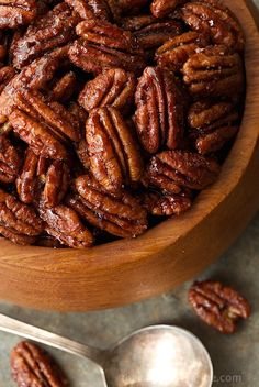 a wooden bowl filled with pecans on top of a table