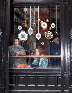 people are looking out the window at ornaments hanging from the bars in front of them