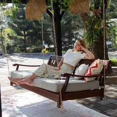 a woman sitting on a porch swing with her feet propped up in the air, resting