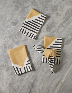 three napkins with black and white designs on them sitting on a gray table top