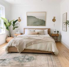 a bedroom with white walls, wooden floors and a large painting on the wall above the bed