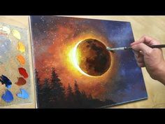 a person is holding a paintbrush in front of a painting with the moon on it