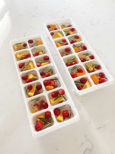 two ice trays filled with fruit and veggies on top of a white counter