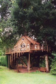 a tree house built into the side of a large green field with trees around it