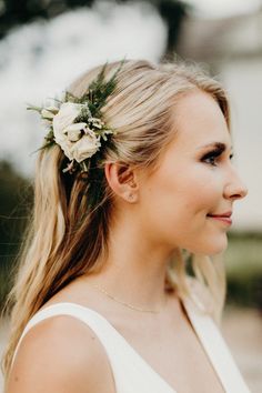 a woman with blonde hair wearing a white dress and flower in her hair, looking off to the side