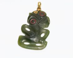 a green and red ceramic figurine sitting on top of a white table next to a gold chain