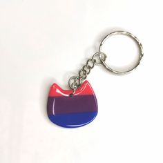 a red, blue and purple cat shaped keychain on a white surface with a silver ring