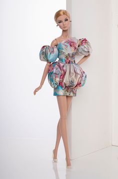 a barbie doll wearing a dress and high heels standing next to a wall with her hands on her hips