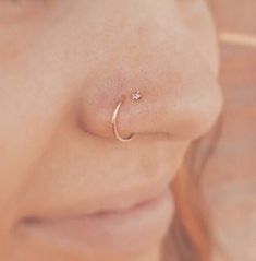 a close up of a woman's nose with a small ring on her nose