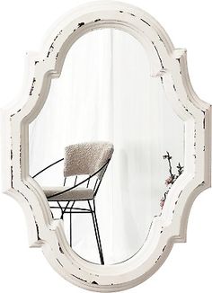 a white mirror sitting on top of a wooden table next to a chair and window