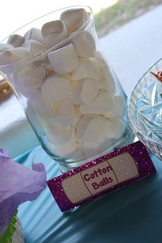 a glass vase filled with white marshmallows on top of a blue table