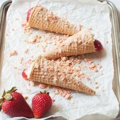 three cones of ice cream with strawberries on a baking sheet, ready to be eaten