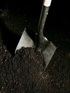 black and white photograph of a shovel in the ground with dirt on it's sides