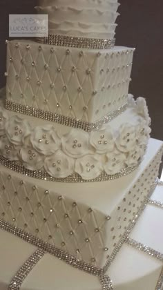 a three tiered wedding cake with white frosting and beaded decorations on top