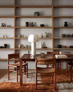 a dining room table with chairs and shelves in the background