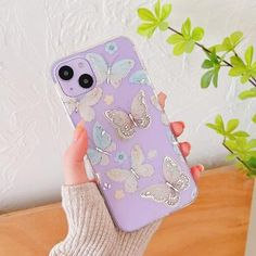 a woman holding up her phone case with butterflies on it