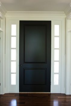 an empty room with a black door and wooden floors