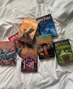 five harry potter books laid out on a white bed with the covers pulled back and folded down