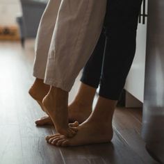 two people standing next to each other on top of a hard wood floored floor