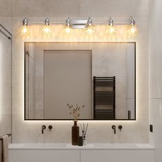 a bathroom mirror with lights above it and two sinks below the mirror, along with a radiator