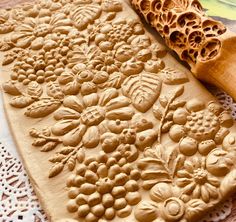 an intricately carved piece of wood next to a wooden rolling pin on a doily