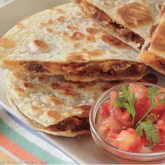 a plate topped with quesadillas and salsa