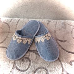 two pairs of blue slippers with lace on them sitting on top of a bed