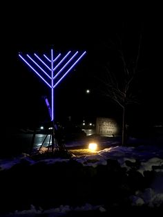 a lighted menorah in the snow at night