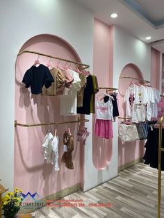 a clothing store with pink walls and clothes hanging on the rack in front of it