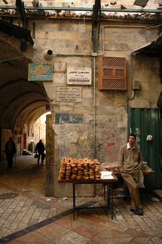 a man sitting in front of a table filled with donuts on the side of a street