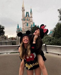 two women in mickey and minnie mouse outfits posing for a photo at the disneyland world