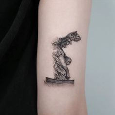 a woman's arm with an angel statue tattoo on the left side of her arm