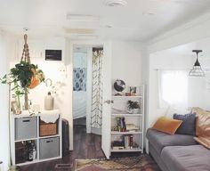 a living room filled with furniture and a book shelf next to a doorway that leads into a bedroom