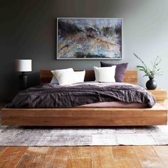 a large bed sitting in the middle of a bedroom next to a painting on the wall