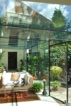 Image: Inside a large all glass room built over a courtyard space. The room is furnished with relaxed rattan sofa seating, a rug and lots of indoor plants Glass Room Extension, Glass Box Extension, Box Extension, Bungalow Extensions, Victorian House Interiors, Home Extension, Small Courtyard Gardens, Room Extensions, Glass Extension