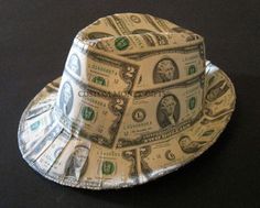 a hat made out of dollar bills on a black surface with the top half rolled up