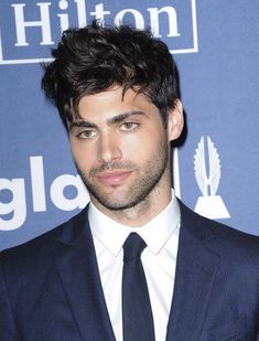 a young man in a suit and tie posing for the camera at an event,