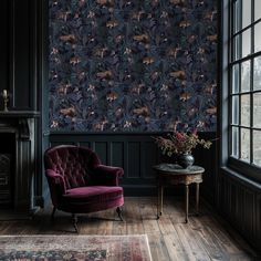 a purple chair sitting in front of a window next to a rug on top of a wooden floor