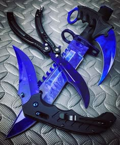 two different types of knifes sitting on top of a bed with black handles and blue blades