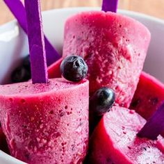 blueberry popsicles in a white bowl with purple sticks sticking out of them