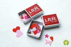 three small boxes with hearts inside sitting on a white surface next to cut outs that spell out the word let's go