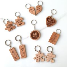 wooden keychains with different designs and words are arranged on a white surface,