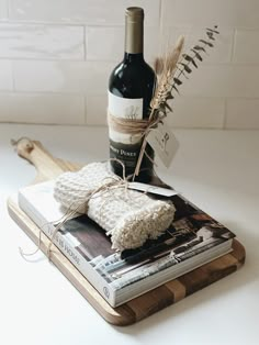 a bottle of wine sitting on top of a book next to a knife and some wheat