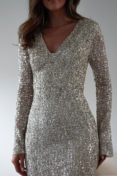 a woman wearing a silver sequin dress